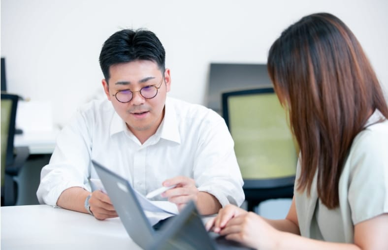 写真：スタッフ2名が書類を見ながらやり取りをしている様子。